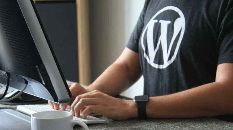 Homem usando camisa preta do WordPress digitando em um computador