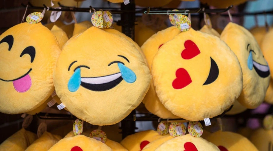 Imagem de loja com almofadas de emojis penduradas em um mostruário