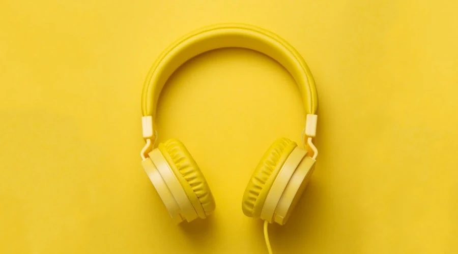Imagem mostra fones de ouvido amarelos sobre uma plataforma de madeira