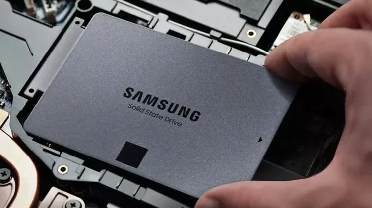 Mão segurando um SSD da Samsung sendo instalado em um notebook