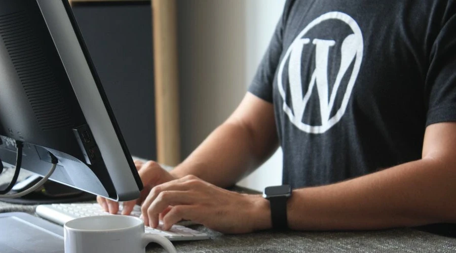 Homem usando camisa preta do WordPress digitando em um computador