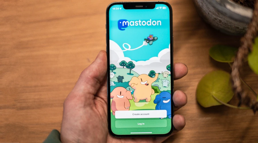 Mão segurando um iPhone com o aplicativo do Mastodon aberto