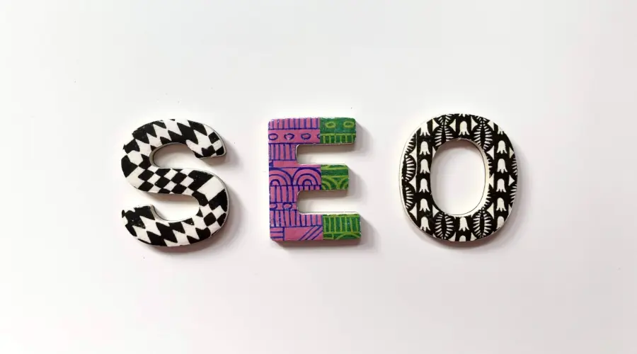 Três biscoitos decorados com cobertura no formato das letras S E O em um mesa da cor branca
