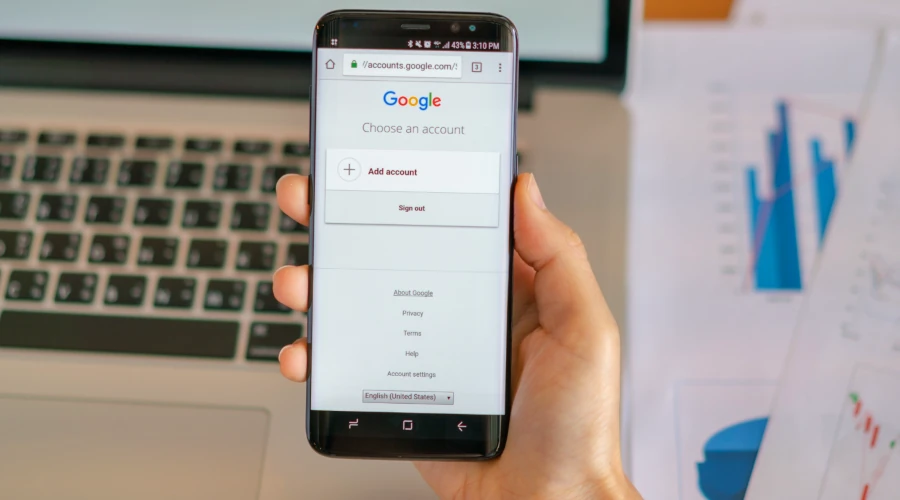 Mão segurando smartphone com tela de login do Google