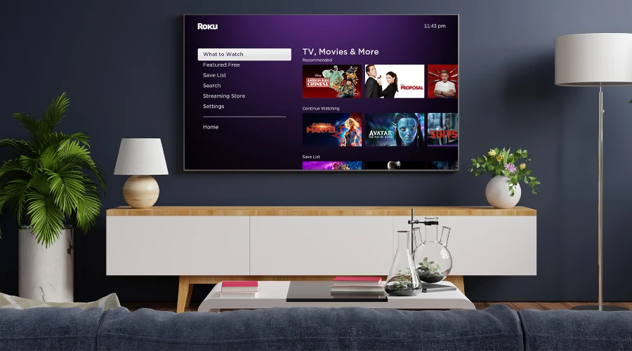 Uma sala com uma TV ligada com a tela inicial do serviço de streaming Roku aberto