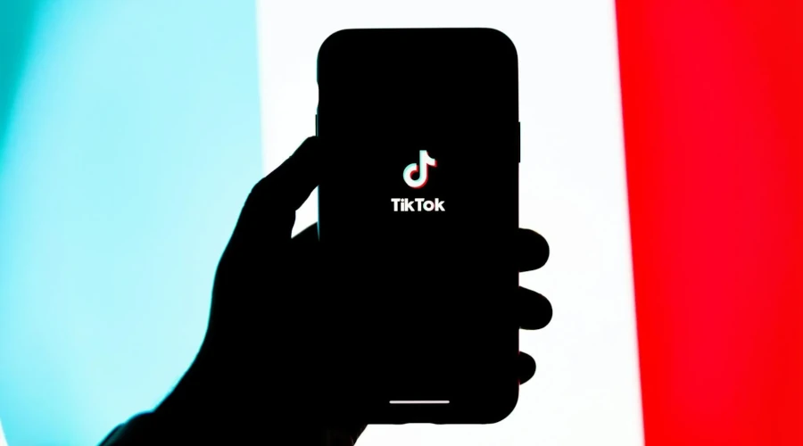Mão segurando smartphone com o TikTok aberto