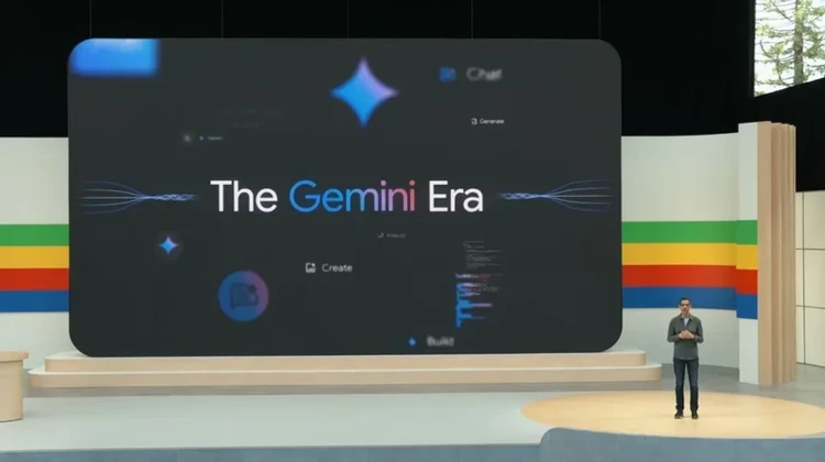 Sundar Pichai apresentando o Google I/O com a frase A Era Gemini num telão ao fundo