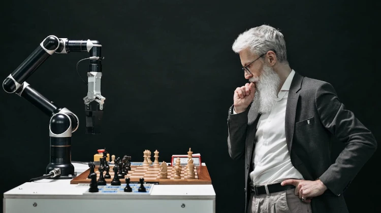 Homem jogando xadrez contra um robô com braço mecânico