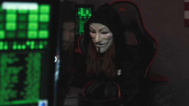 Hacker com máscara do Guy Fawkes anonymous em frente a um computador