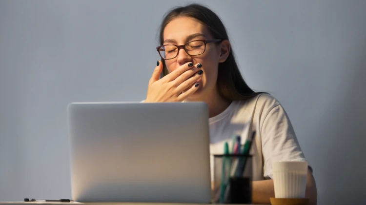 mulher bocejando na frente de um notebook