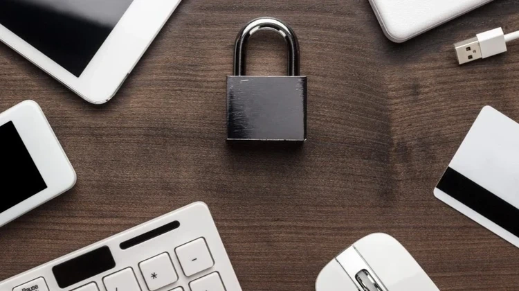 Imagem mostra um enorme cadeado sobre uma mesa rodeado por vários dispositivos eletrônicos