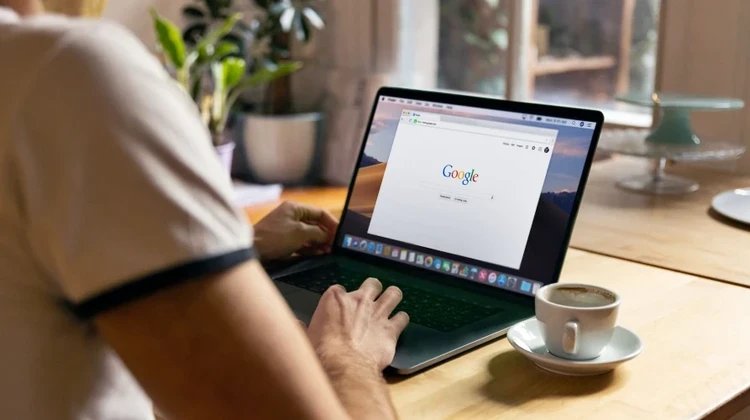 Homem usa um apple mackbook em um café ou restaurante. Ele está fazendo uma busca no google