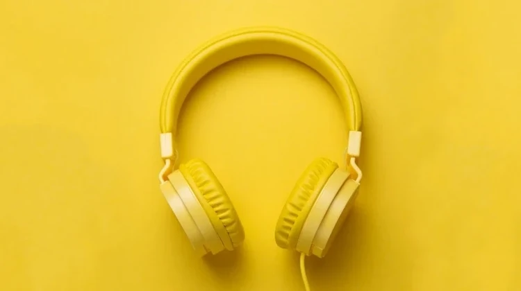 Imagem mostra fones de ouvido amarelos sobre uma plataforma de madeira