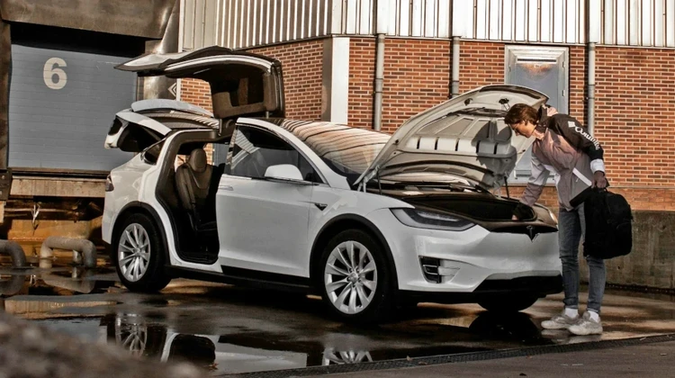 Homem tirando objetos da mala de um SUV Tesla Model X na cor branca